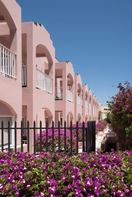 a fence in front of a building with purple flowers at Vila Gale Collection Praia in Albufeira