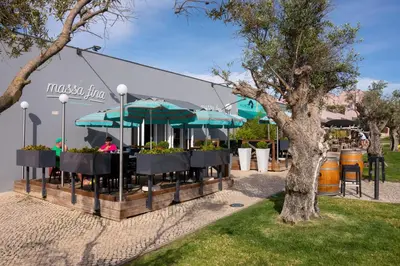 a restaurant with tables and umbrellas in a park at Vila Gale Collection Praia in Albufeira