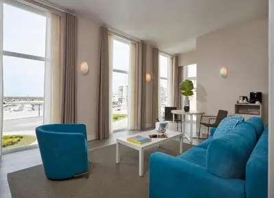 a living room with a blue couch and chairs at Occidental Faro in Faro