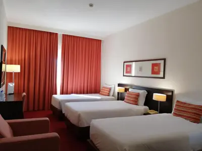 a hotel room with two beds and a mirror at Hotel Monaco in Faro