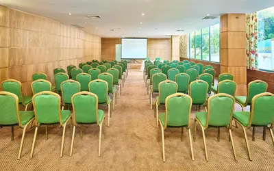 a conference room with green chairs and a screen at Hotel Baia Grande in Albufeira