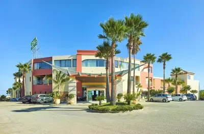 a building with palm trees in a parking lot at Hotel Baia Grande in Albufeira