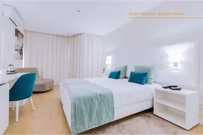a bedroom with a large white bed with blue pillows at Auramar Beach Resort in Albufeira