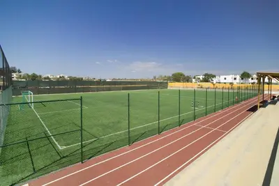 a tennis court with a field and a fence at Alfagar Alto da Colina in Albufeira