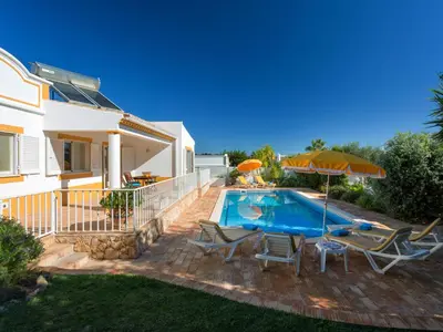 a house with a swimming pool with chairs and an umbrella at Villa Villa Natura by Interhome in Guia
