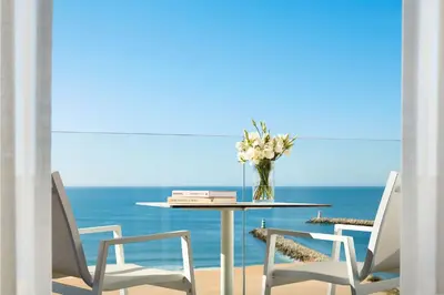 a table with chairs and a vase of flowers on it at Tivoli Marina Vilamoura in Vilamoura