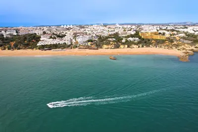 a boat in the water next to a beach at Monica Isabel Beach Club in Albufeira