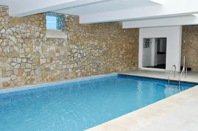 a swimming pool with a stone wall at Martinhal Quinta Family Resort in Quinta do Lago