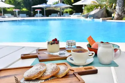 a tray of bread and coffee next to a pool at Martinhal Quinta Family Resort in Quinta do Lago