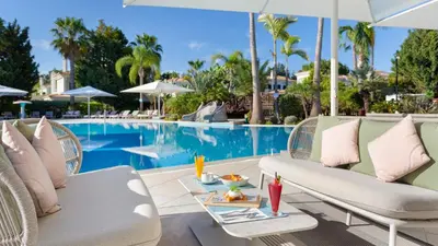 a resort pool with chairs and a table with food on it at Martinhal Quinta Family Resort in Quinta do Lago