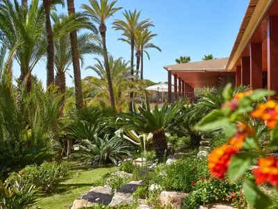 a garden with palm trees and flowers in front of a house at Ria Park Hotel & Spa in Vale do Lobo