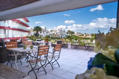 a patio with tables and chairs on a balcony at Hotel da Aldeia - Adults Only in Albufeira