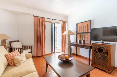 a living room with a couch and a television at Hotel da Aldeia - Adults Only in Albufeira