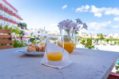 a glass of orange juice and croissants on a table at Hotel da Aldeia - Adults Only in Albufeira