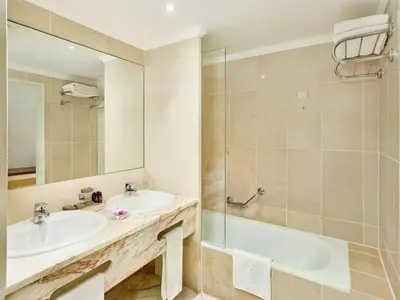 a bathroom with a sink and a tub and a mirror at Ria Park Garden Hotel in Vale do Lobo