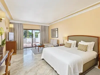 a bedroom with a large bed and a living room at Ria Park Garden Hotel in Vale do Lobo