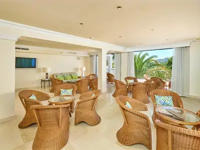 a living room with wicker chairs and tables at Ria Park Garden Hotel in Vale do Lobo