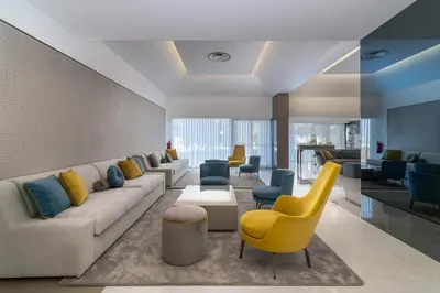 a living room with a couch and a yellow chair at Jupiter Albufeira Hotel - Family & Fun - All Inclusive in Albufeira
