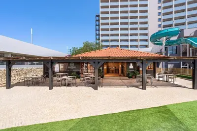 a pavilion with tables and chairs and a building at Jupiter Albufeira Hotel - Family & Fun - All Inclusive in Albufeira