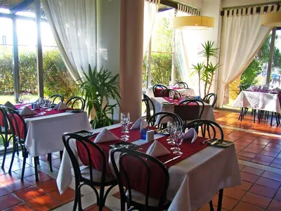 a dining room with tables with red and white tablecloths at Dom Pedro Portobelo in Vilamoura