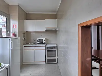 a small kitchen with white cabinets and a refrigerator at Dom Pedro Portobelo in Vilamoura