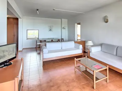 a living room with two white couches and a tv at Dom Pedro Portobelo in Vilamoura