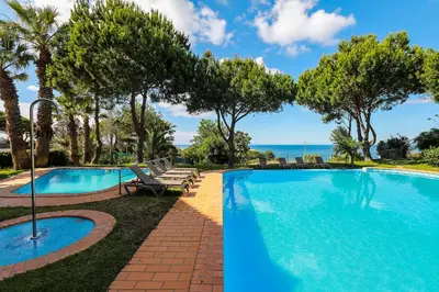 a pool with chairs and trees and the ocean at Quinta Pedra Dos Bicos in Albufeira