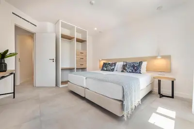 a white bedroom with a bed and a table at Clube Maria Luisa in Albufeira