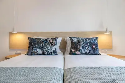 a bedroom with two beds with blue pillows at Clube Maria Luisa in Albufeira