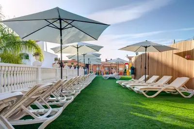 a row of lounge chairs with umbrellas on the grass at Choromar Apartments in Albufeira