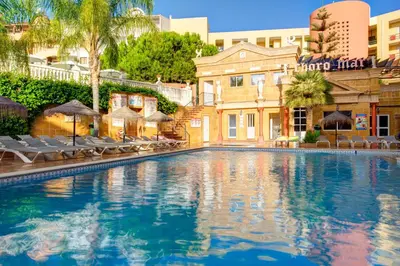 a swimming pool at a resort with chairs and umbrellas at Choromar Apartments in Albufeira