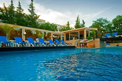 a swimming pool with blue chairs and a building at Hotel Balaia Mar in Albufeira