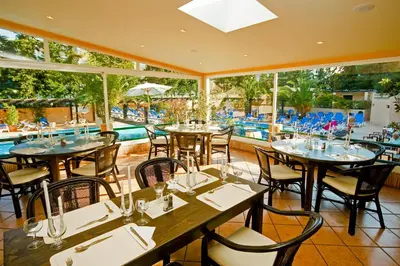 a restaurant with tables and chairs and a pool at Apartamentos da Balaia in Albufeira