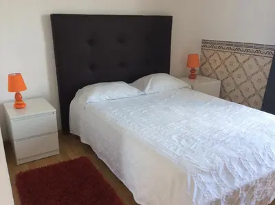 a bedroom with a white bed with a black headboard and two lamps at Golda Sol in Loulé