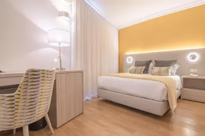 a bedroom with a bed and a desk and a chair at Loule Jardim Hotel in Loulé