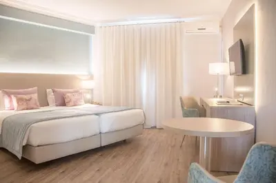 a hotel room with a bed and a table and chairs at Loule Jardim Hotel in Loulé