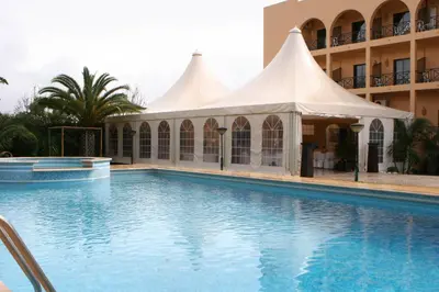 a swimming pool in front of a building with a tent at Hotel Parque das Laranjeiras in Vilamoura