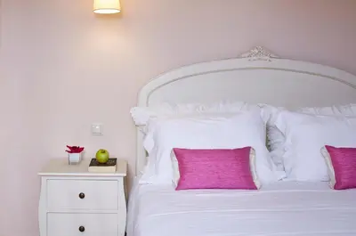 a bedroom with a white bed with a pink pillow at Hotel Parque das Laranjeiras in Vilamoura