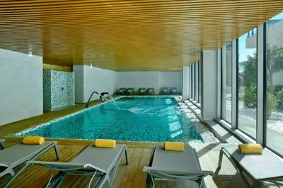 a swimming pool in a hotel room with chairs and a pool at Alisios in Albufeira