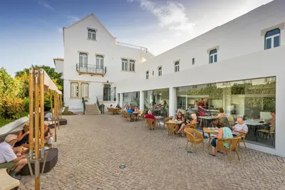 a group of people sitting at tables outside a building at Vila Recife Hotel in Albufeira