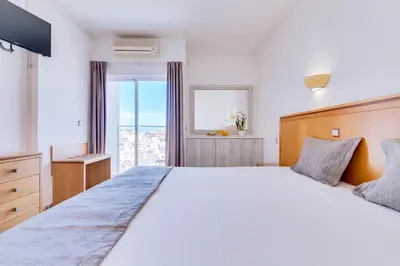 a bedroom with a large white bed and a window at Vila Recife Hotel in Albufeira