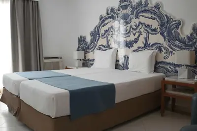 a bedroom with a large bed with a blue and white headboard at Hotel Apartamento Do Golfe in Vilamoura