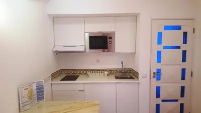 a small kitchen with white cabinets and a microwave at Apartamentos Turisticos Soldoiro in Albufeira