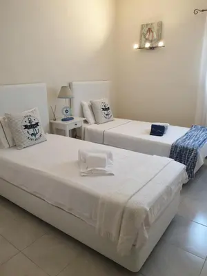 two beds in a white room with two tables at Vilamoura-Nautic Apartment in Vilamoura