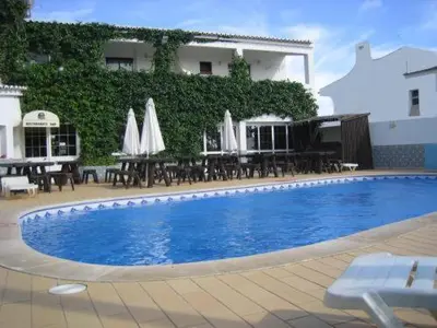 a swimming pool in front of a building with tables and umbrellas at Torre Velha AL in Albufeira