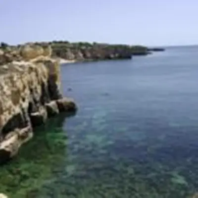 a large body of water next to a rocky shore at Torre Velha AL in Albufeira