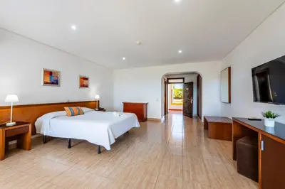 a hotel room with a bed and a flat screen tv at Hotel Pinhal do Sol in Quarteira