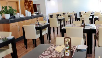 a restaurant with tables and white chairs and bottles of beer at Parque Mourabel, Oásis Village & Pé do Lago in Vilamoura