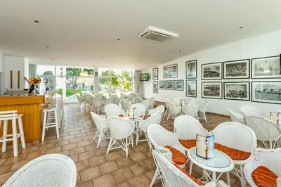 a restaurant with white chairs and tables and pictures on the walls at Pateo Village in Albufeira