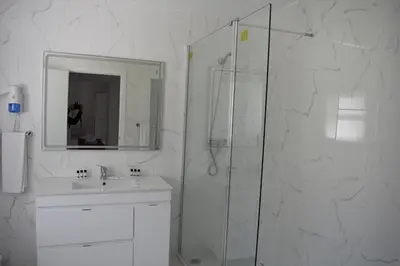a white bathroom with a shower and a sink at Pateo Village in Albufeira